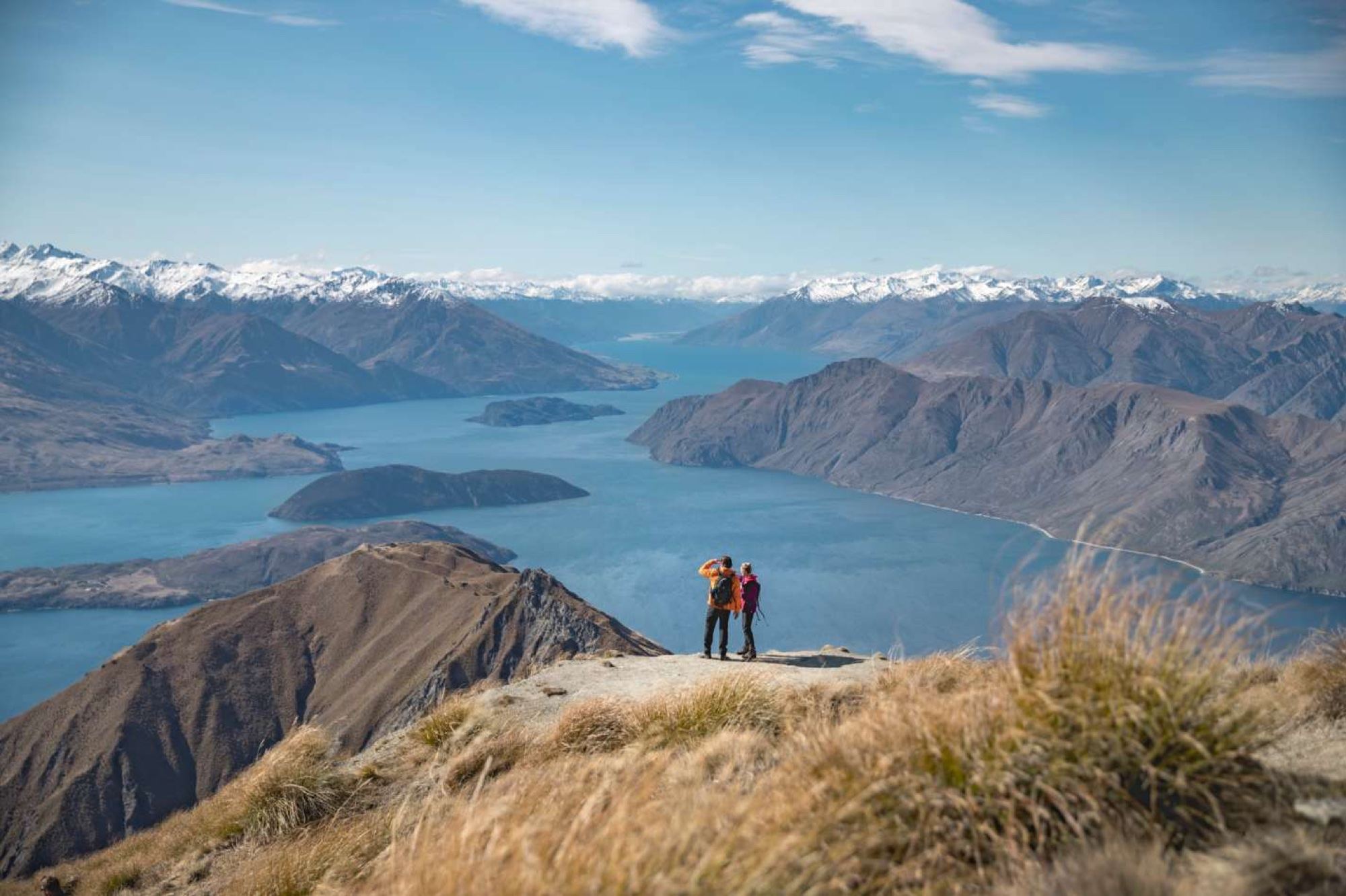 Hikers on Roys Peak looking out over Lake Wānaka and the Southern Alps
